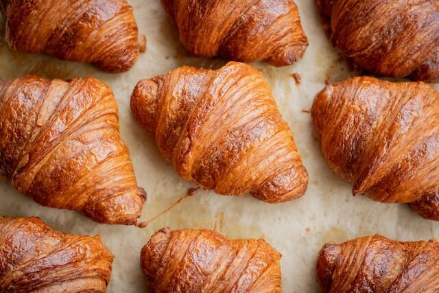 A group of croissants on a baking sheetDescription automatically generated