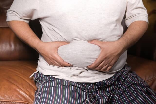 A person holding his stomachDescription automatically generated