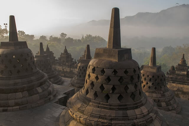 A close-up of a temple with Borobudur in the backgroundDescription automatically generated