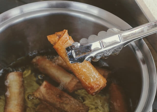 A tongs holding a piece of food in a potDescription automatically generated