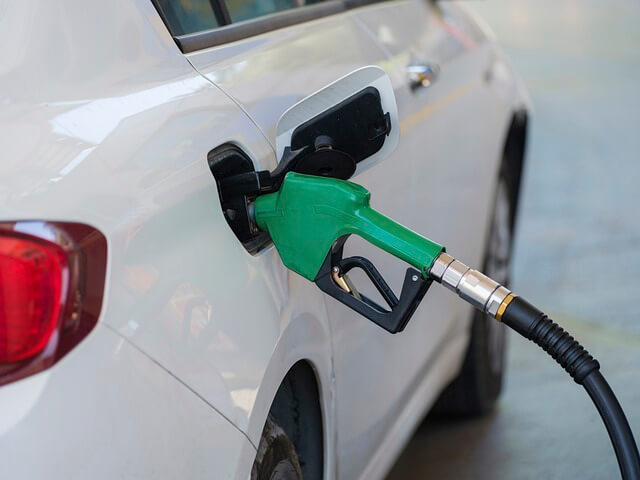 A white car with a green gas pumpDescription automatically generated